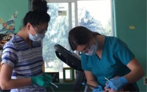 Holly jones working with a patient in a garage with a student watching her